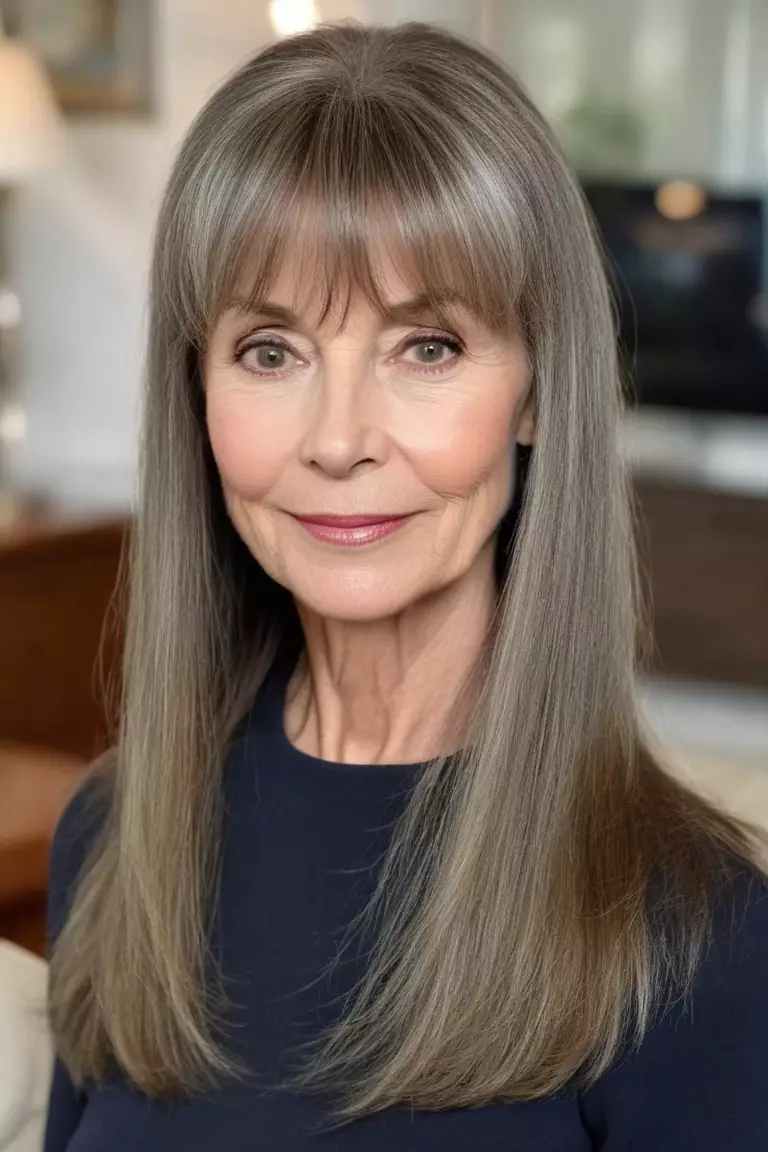 A photo of a 61-year-old Catherine, long straight hair with wispy bangs, front view, living room background