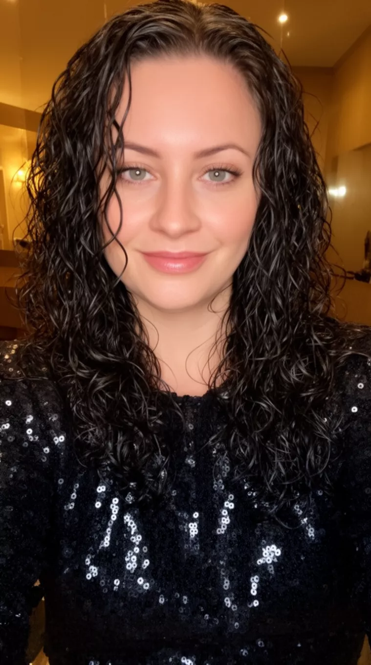 selfie of a 30-year-old woman wearing a black sequin top with a Defined wet-look curls for evening