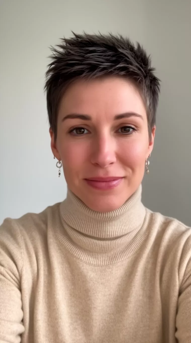 selfie of a 35-year-old woman wearing a beige turtleneck with a Piecey Pixie hairstyle, minimal background