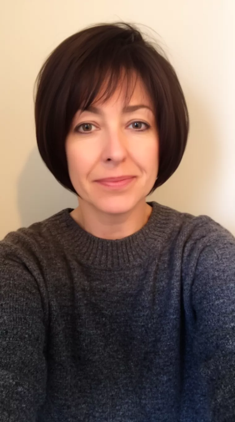 selfie of a 41-year-old woman wearing a charcoal grey sweater with a Stacked Bob hairstyle, minimal background