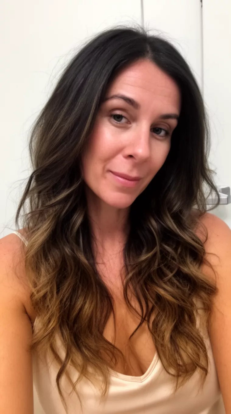 casual close-up photo of a 38-year-old woman wearing a light-colored camisole top with a long wavy dark brown hair with subtle highlights hairstyle, minimal background