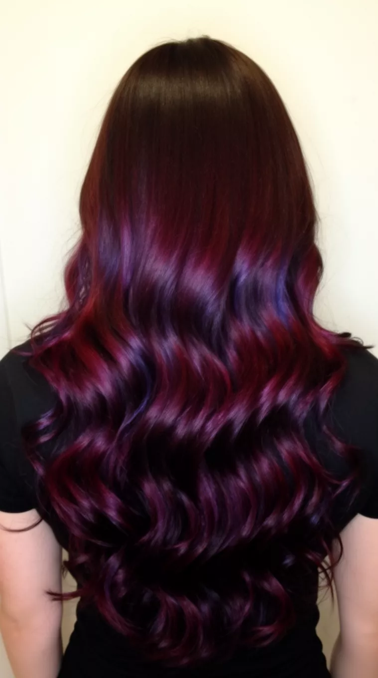 casual photo of a 31-year-old woman wearing a black top with a dark brown hair featuring dramatic, rich burgundy and purple iridescent highlights colored very long, wavy hairstyle, back view, minimal background.