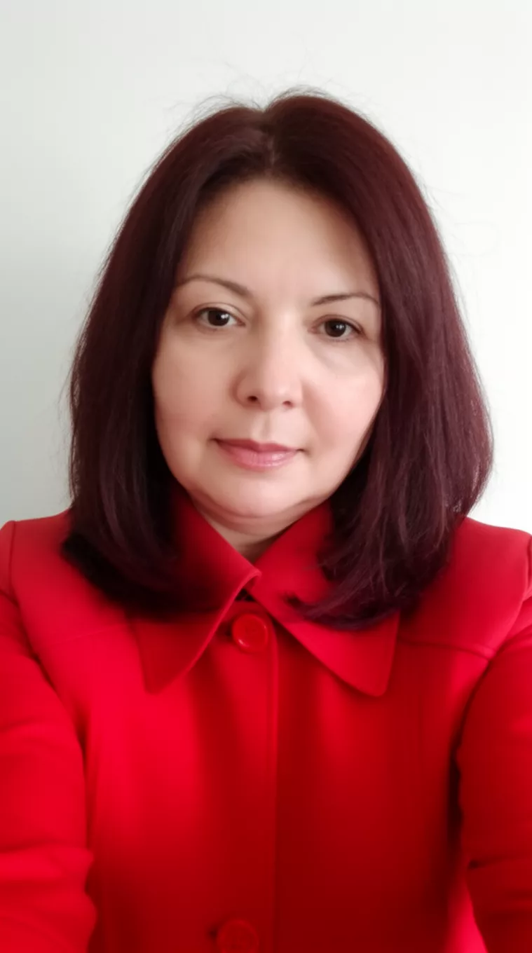 selfie of a 43-year-old woman wearing a red structured jacket with a dark red colored shoulder-length hairstyle, front view, minimal background.