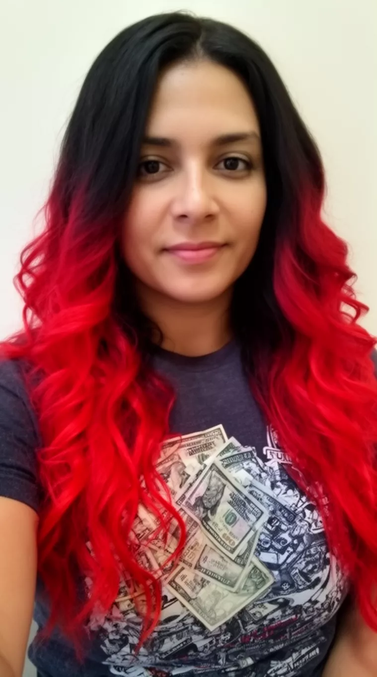 selfie of a 33-year-old woman wearing a dark graphic t-shirt with a dark hair with bright red money pieces colored long wavy hairstyle, front view, minimal background.