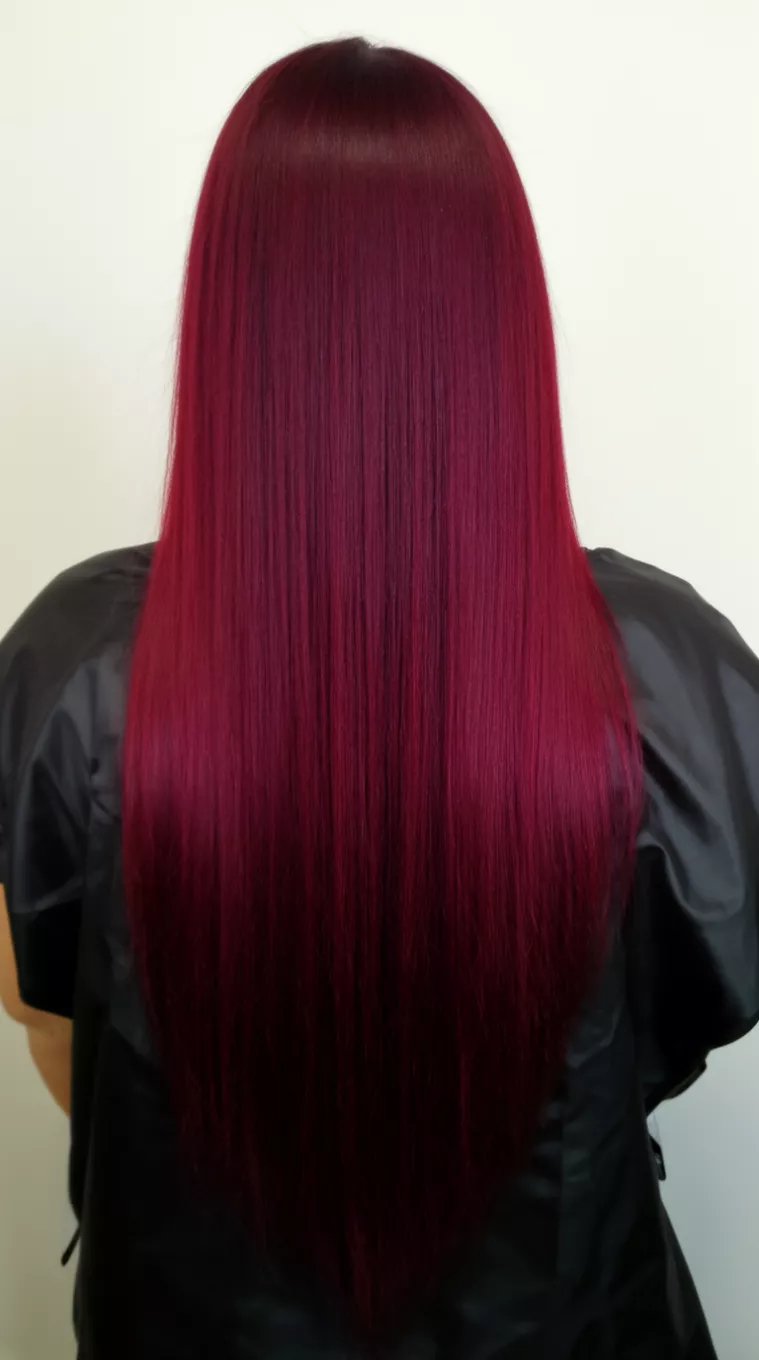 casual photo of a 41-year-old woman wearing a black styling cape with a deep burgundy colored very long straight hairstyle, back view, minimal background.