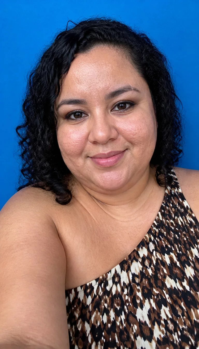 Joyful Blue Background Curls selfie of a 30-year-old plus size Latina woman with a chubby face and delicate nose. The skin is heavily textured with a complex pattern of dimples and a faint, thin scar traversing the left eyebrow. The eyes are brown. She is wearing a patterned one-shoulder dress with a dark curly hairstyle, front view, blue background.