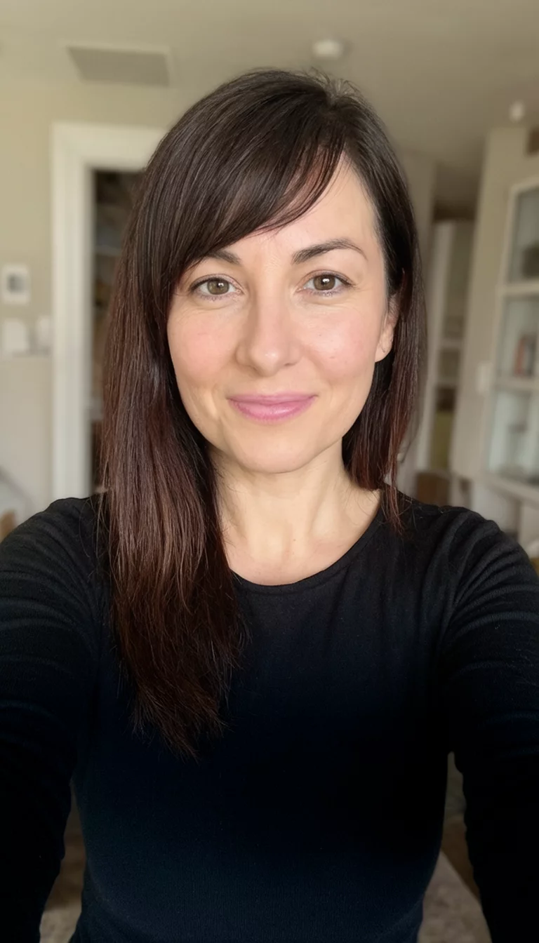 selfie of a 30-year-old woman wearing a black long-sleeved top with a dark brown hair colored side-swept bangs hairstyle, front view, indoor home background