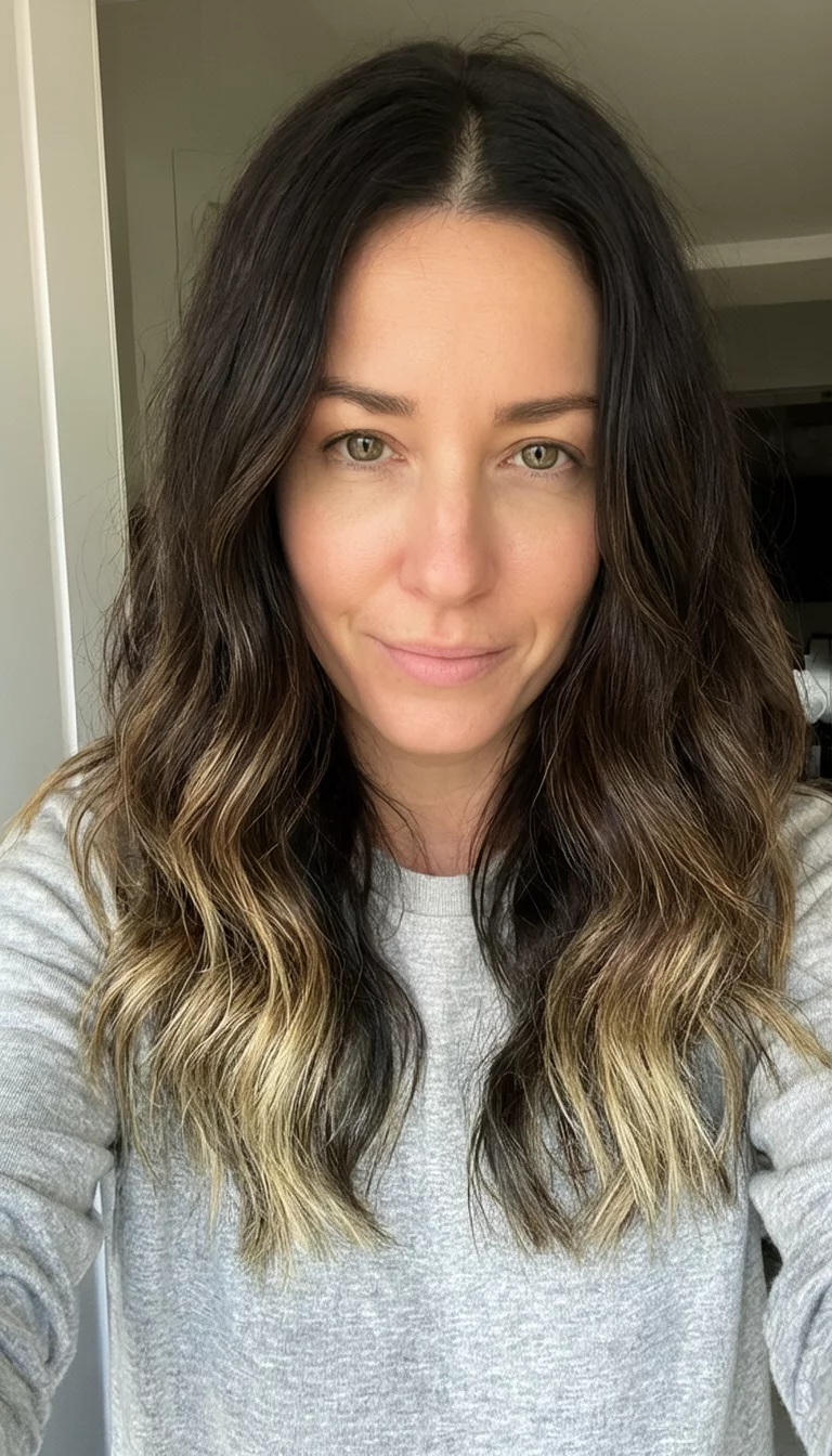 Dark Brown Balayage Hands On Style selfie of a 31-year-old woman wearing a casual top with a long, wavy dark brown medium length hairstyle with blonde balayage, front view, indoor setting