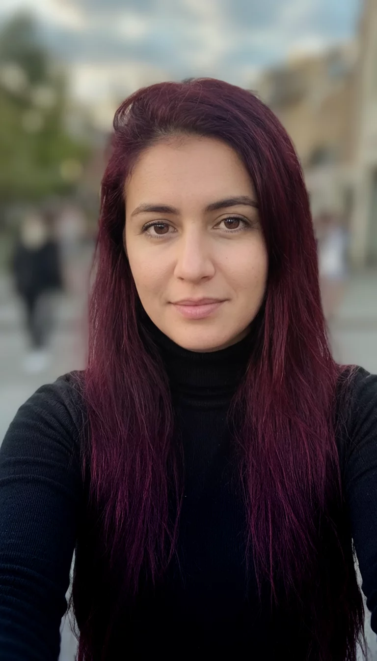 Deep Black Cherry selfie of a 26-year-old woman wearing a black turtleneck with a dark burgundy colored long hairstyle, front view, blurred background