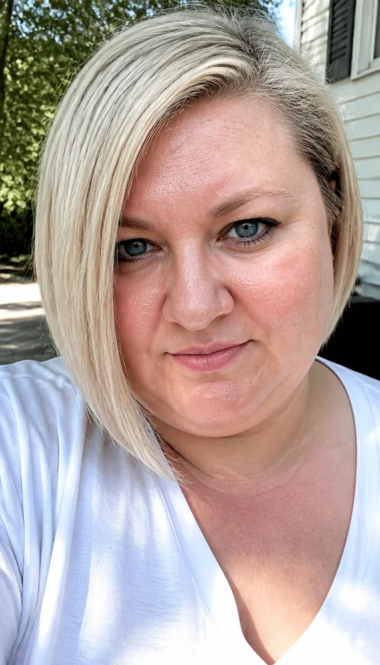 Modern Platinum Asymmetric Bob selfie of a 36-year-old plus size Caucasian woman with a chubby face and a pointed nose. The skin is heavily textured with a complex pattern of visible pores and a faint, thin scar traversing the left eyebrow. The eyes are deep-set blue. She is wearing a white top with a platinum blonde asymmetric bob hairstyle that is longer in the front and shorter in the back, front view, outdoor sunlight.